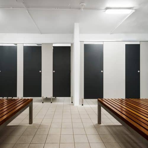 Overhead braced partitions provide structural stability in commercial restrooms.